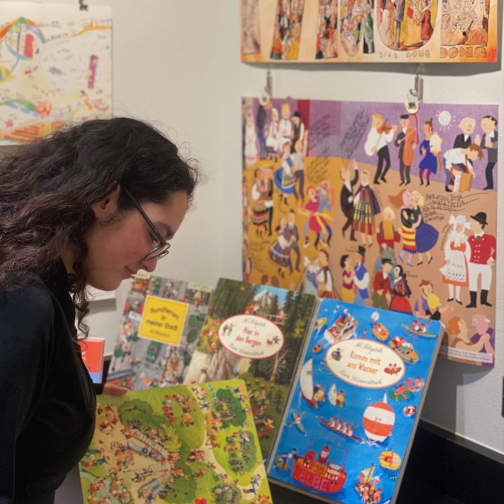 Young woman examines Ali Mitgutsch books closely.