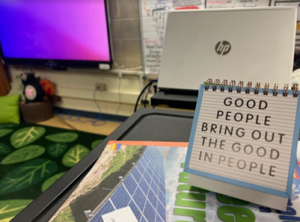 The quote "Good people bring out the good in people" is displayed on a desk.